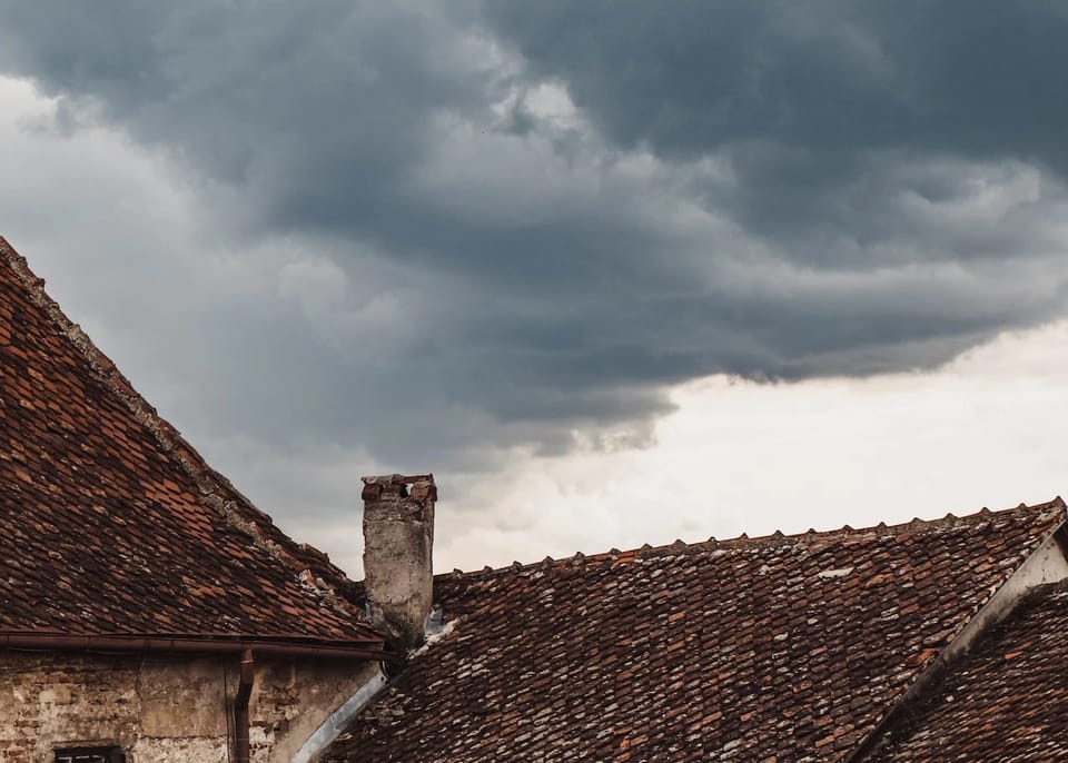 Terra cotta roofs and a chimney underneath stormy skies