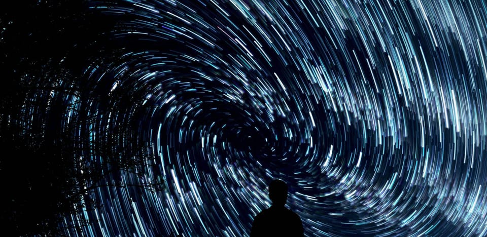 The silhouette of a person's head and shoulders in front of a sweeping solar system's analemma